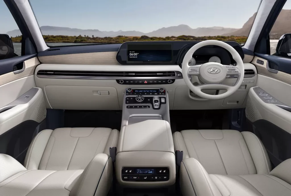 Interior Hyundai Palisade Signature (varian Indonesia) menampilkan desain dasbor mewah dengan dominasi warna cerah, aksen woodgrain, serta tombol transmisi model "shift-by-wire" di konsol tengah.